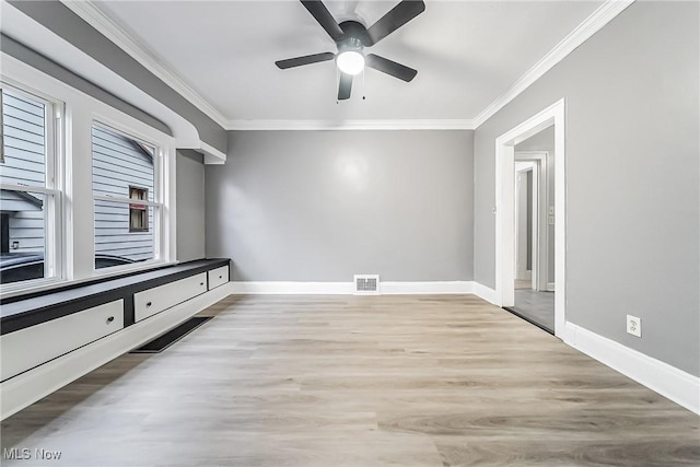 spare room with visible vents, baseboards, wood finished floors, and crown molding