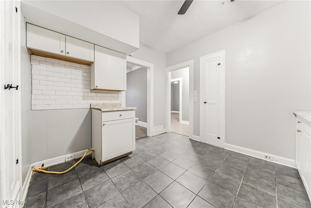 kitchen featuring backsplash, baseboards, ceiling fan, tile patterned floors, and white cabinetry