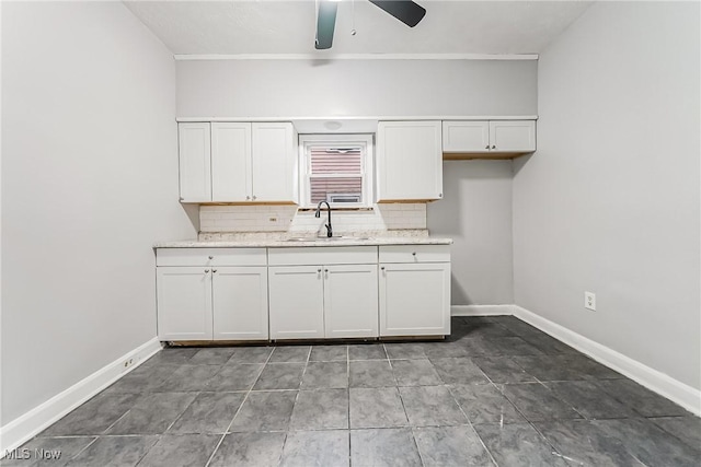 kitchen featuring a ceiling fan, a sink, tasteful backsplash, white cabinets, and baseboards