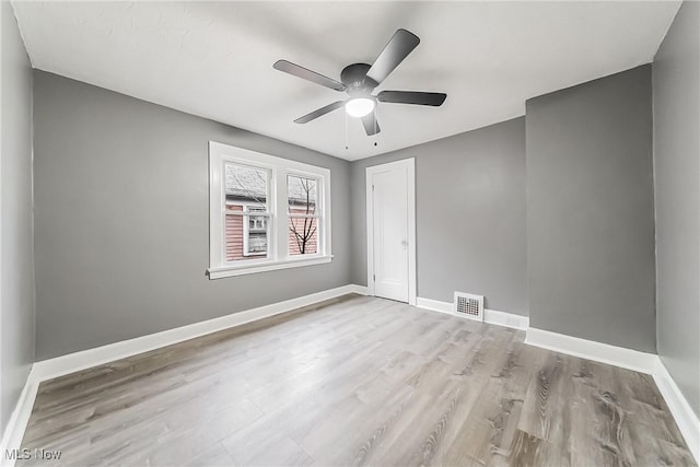 empty room featuring a ceiling fan, wood finished floors, baseboards, and visible vents