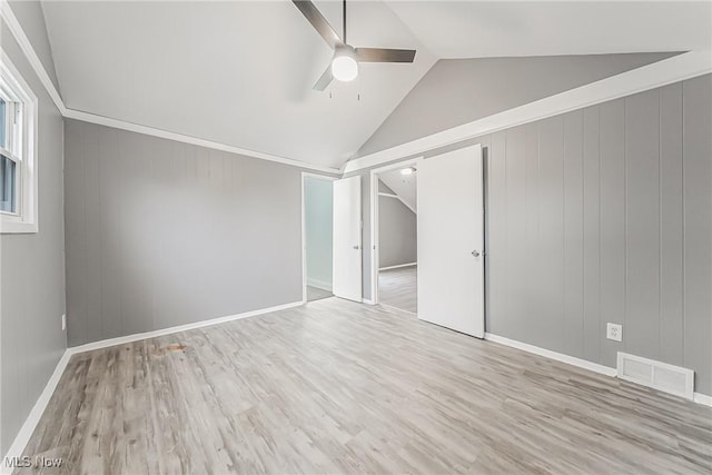 spare room with visible vents, baseboards, vaulted ceiling, wood finished floors, and a ceiling fan