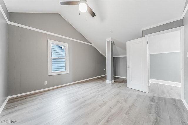 unfurnished bedroom featuring a ceiling fan, lofted ceiling, light wood-style floors, and baseboards