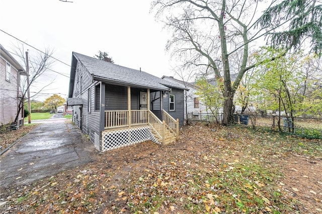 view of front facade with a shingled roof and fence