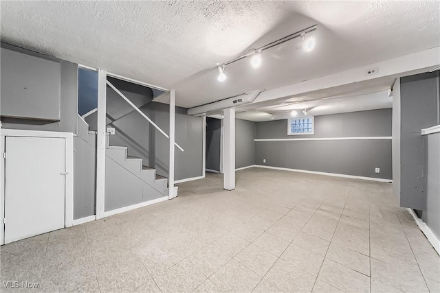 below grade area featuring stairway, baseboards, and a textured ceiling