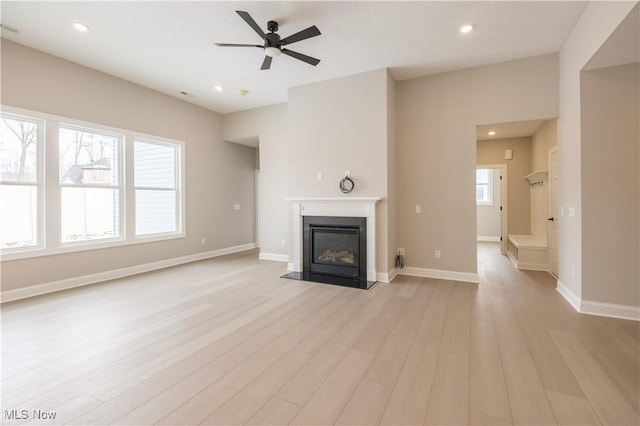 unfurnished living room with ceiling fan, light wood-style flooring, a fireplace with flush hearth, recessed lighting, and baseboards