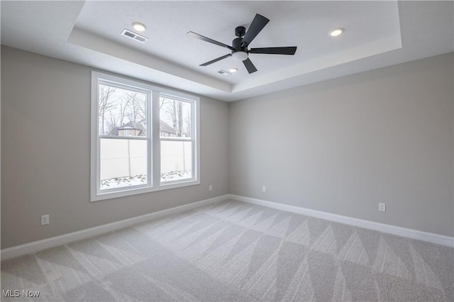 unfurnished room featuring a tray ceiling, light carpet, baseboards, a ceiling fan, and recessed lighting