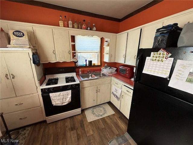 kitchen featuring a sink, open shelves, dark wood finished floors, freestanding refrigerator, and gas range