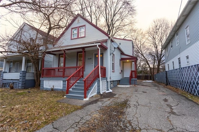 view of front of property with aphalt driveway, covered porch, and fence