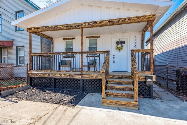 view of exterior entry featuring a porch and fence