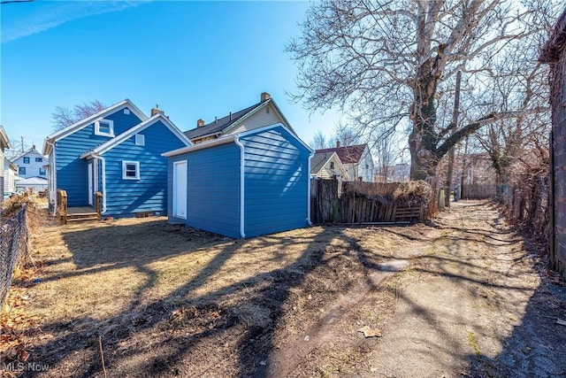 back of house with a storage shed, an outbuilding, fence private yard, and a chimney