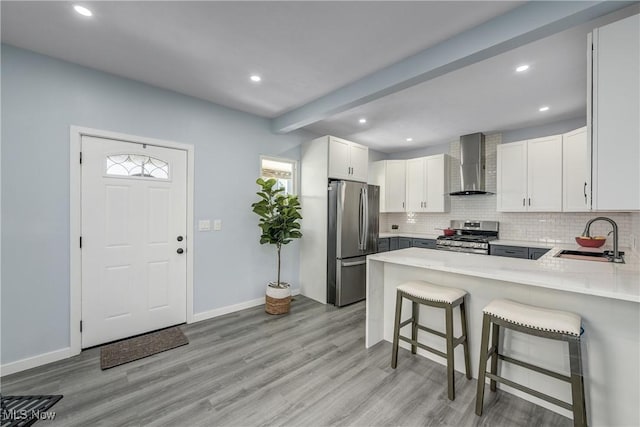 kitchen featuring wall chimney exhaust hood, plenty of natural light, appliances with stainless steel finishes, and a sink