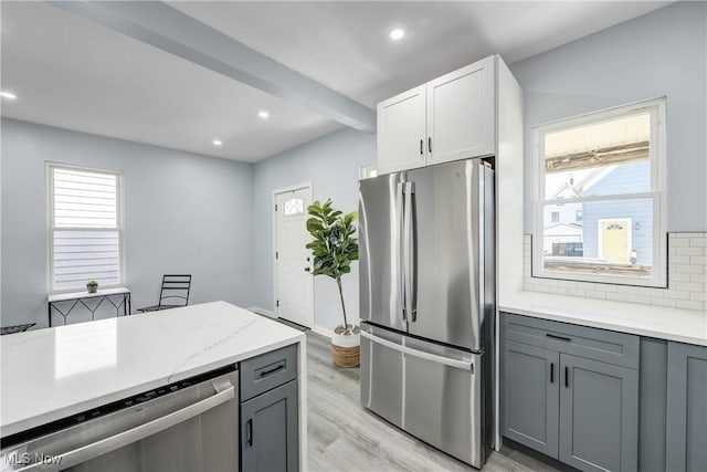 kitchen with light wood-type flooring, stainless steel appliances, tasteful backsplash, and gray cabinets