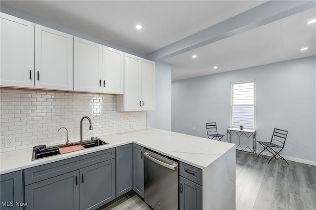 kitchen with a peninsula, light wood-style flooring, gray cabinets, a sink, and dishwasher