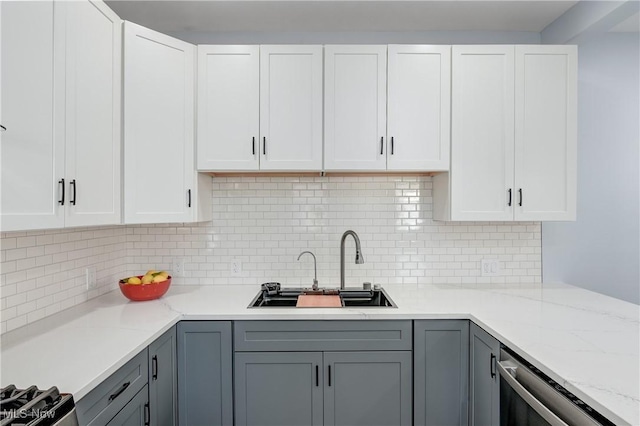 kitchen with a sink, gray cabinetry, and white cabinetry