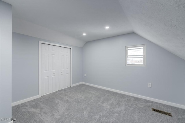 additional living space featuring vaulted ceiling, carpet flooring, baseboards, and visible vents