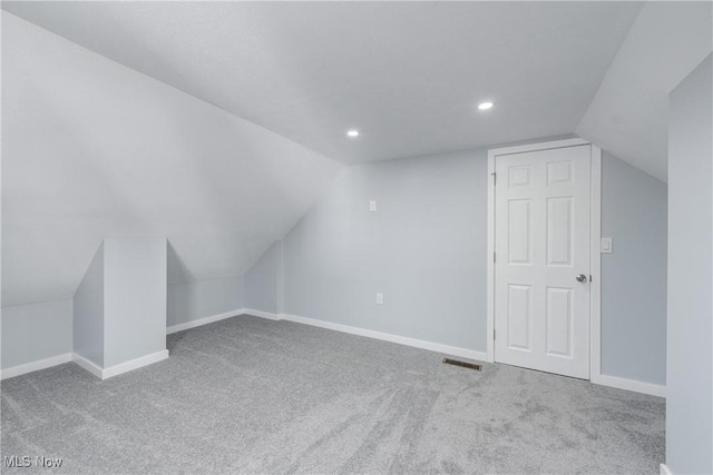 additional living space featuring carpet, baseboards, and vaulted ceiling