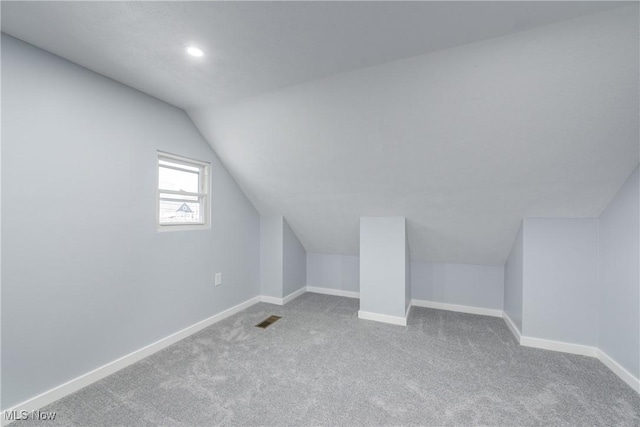 bonus room featuring carpet flooring, visible vents, baseboards, and vaulted ceiling