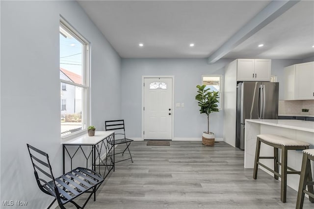 interior space with beam ceiling, light wood-style flooring, recessed lighting, and baseboards