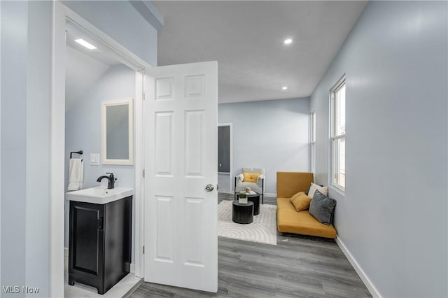 interior space featuring a sink, recessed lighting, baseboards, and wood finished floors