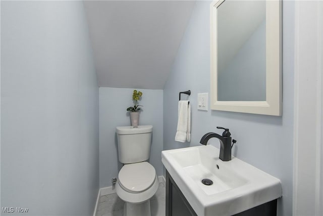 bathroom with vanity, baseboards, vaulted ceiling, toilet, and marble finish floor