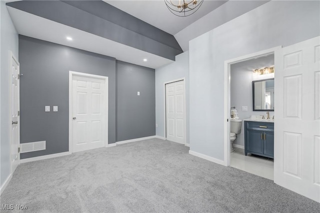 unfurnished bedroom with light colored carpet, ensuite bathroom, baseboards, and a sink