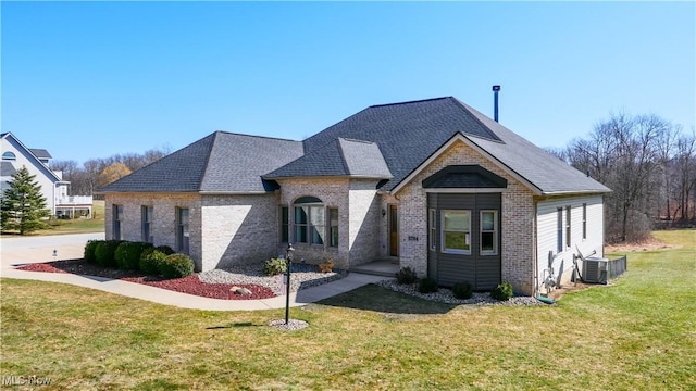 french country style house with brick siding, central AC unit, a front yard, and a shingled roof