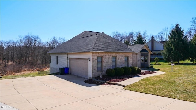 view of home's exterior featuring driveway, roof with shingles, an attached garage, a yard, and brick siding