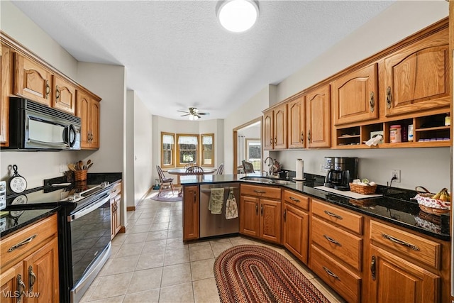 kitchen with black appliances, a sink, a peninsula, light tile patterned flooring, and brown cabinetry