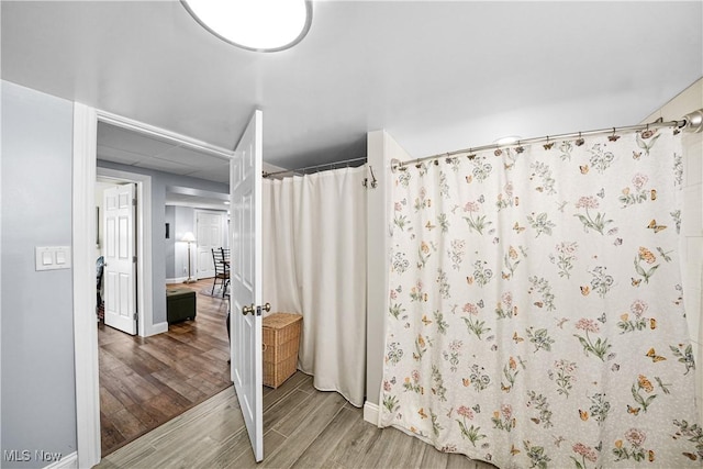 bathroom featuring a drop ceiling, curtained shower, baseboards, and wood finished floors