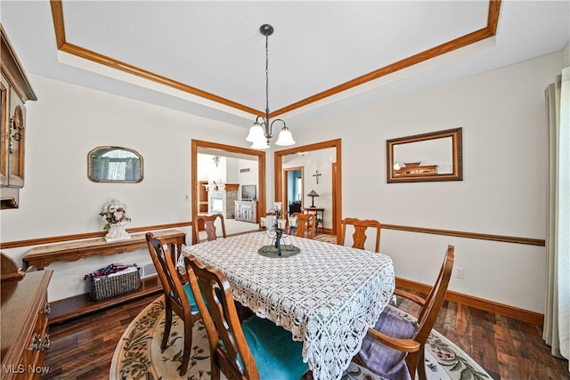 dining space with a raised ceiling, a notable chandelier, baseboards, and dark wood-type flooring