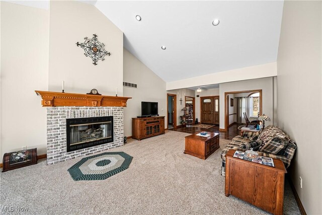 living area featuring a fireplace, visible vents, carpet floors, and high vaulted ceiling