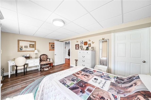 bedroom with wood finished floors, baseboards, and a drop ceiling