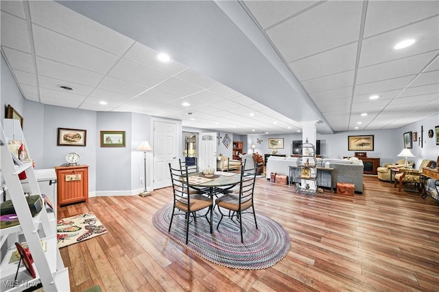 dining area featuring recessed lighting, baseboards, a paneled ceiling, and light wood-style flooring