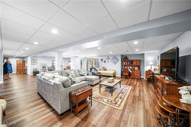 living area with recessed lighting, a paneled ceiling, wood-type flooring, and ornate columns