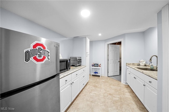 kitchen with a sink, recessed lighting, stainless steel appliances, white cabinets, and light stone countertops