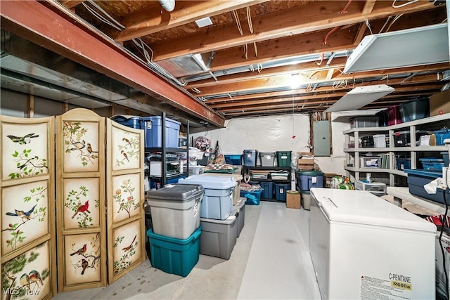 unfinished basement featuring electric panel and refrigerator