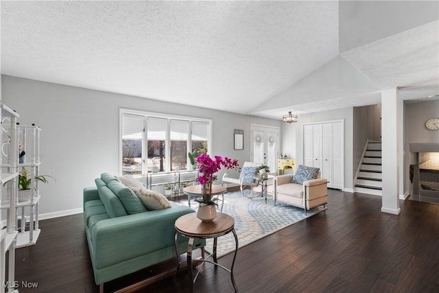 living room with a textured ceiling, wood finished floors, stairway, baseboards, and lofted ceiling