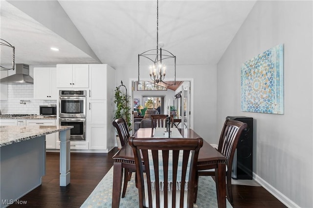 dining room featuring lofted ceiling, dark wood-style floors, baseboards, and a chandelier