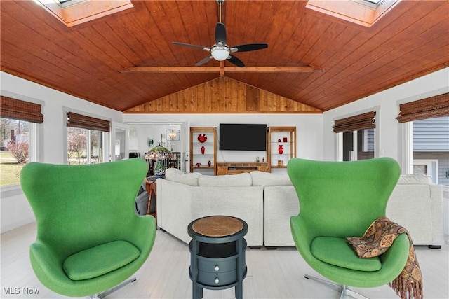 living room featuring a ceiling fan, lofted ceiling with skylight, wood ceiling, and light wood-style floors