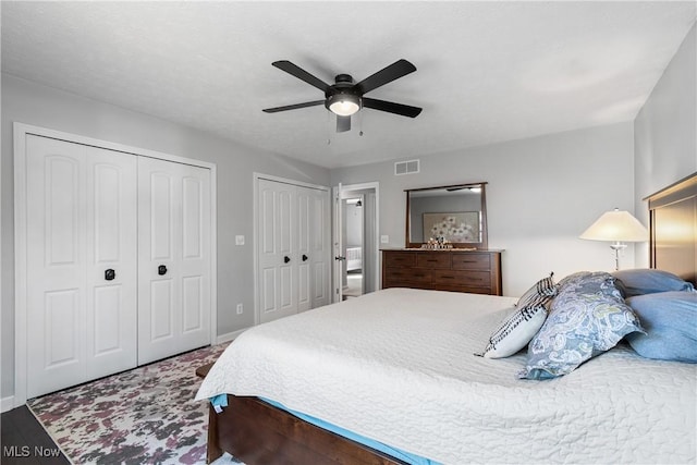 bedroom featuring visible vents, multiple closets, baseboards, and a ceiling fan