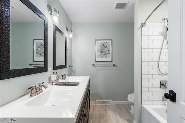 bathroom featuring double vanity, visible vents, toilet, and a sink