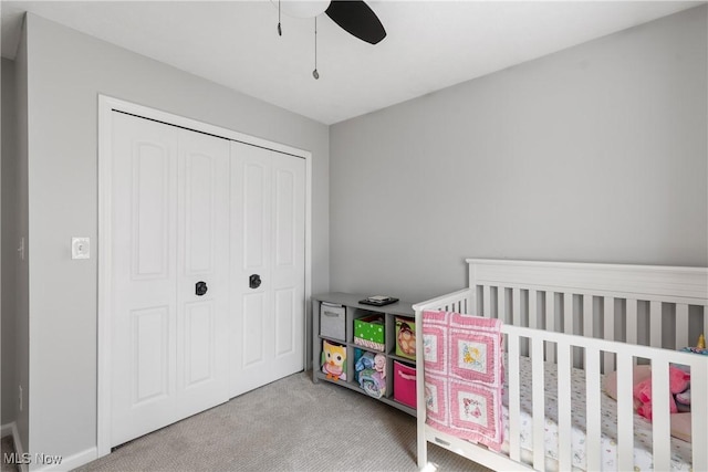 carpeted bedroom featuring a closet, ceiling fan, and a nursery area