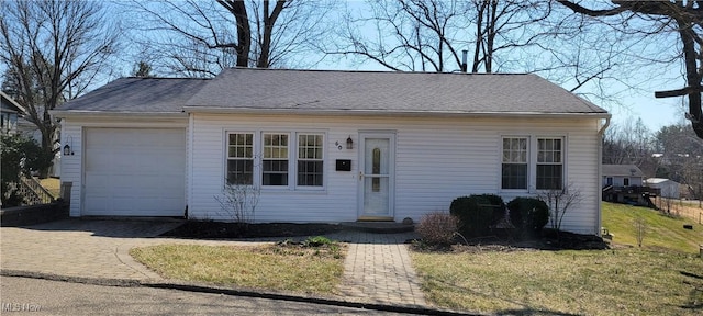 view of front of property featuring decorative driveway, an attached garage, roof with shingles, and a front lawn