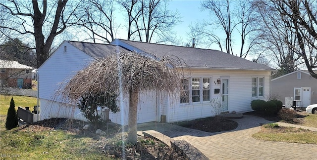 view of front facade featuring decorative driveway and roof with shingles