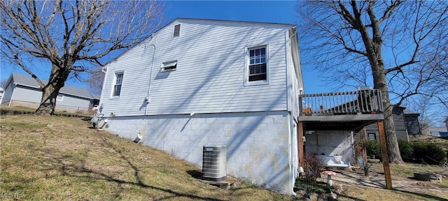 view of property exterior with cooling unit, a lawn, and a wooden deck