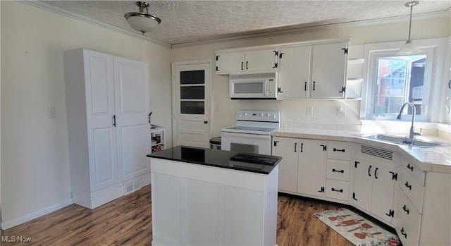 kitchen featuring white appliances, a textured ceiling, dark wood-type flooring, and a sink