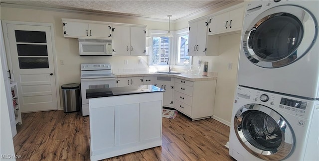 laundry room featuring a textured ceiling, wood finished floors, a sink, and stacked washing maching and dryer