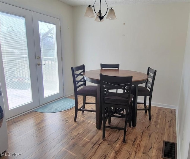 dining space with visible vents, a healthy amount of sunlight, wood finished floors, and french doors