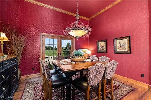 dining room featuring wallpapered walls, wood finished floors, and ornamental molding