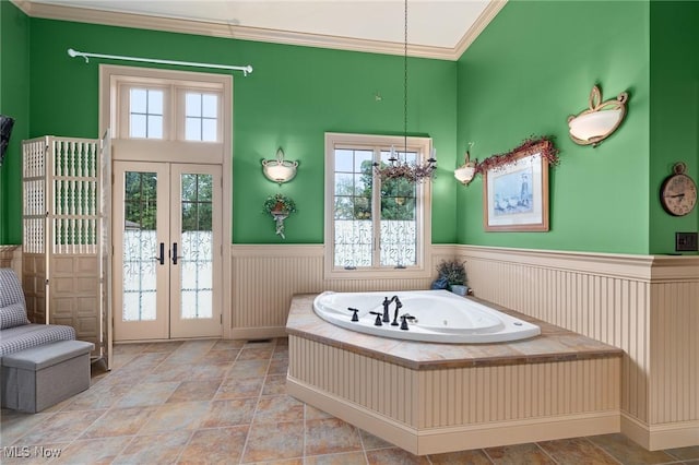 bathroom featuring a notable chandelier, french doors, wainscoting, crown molding, and a bath